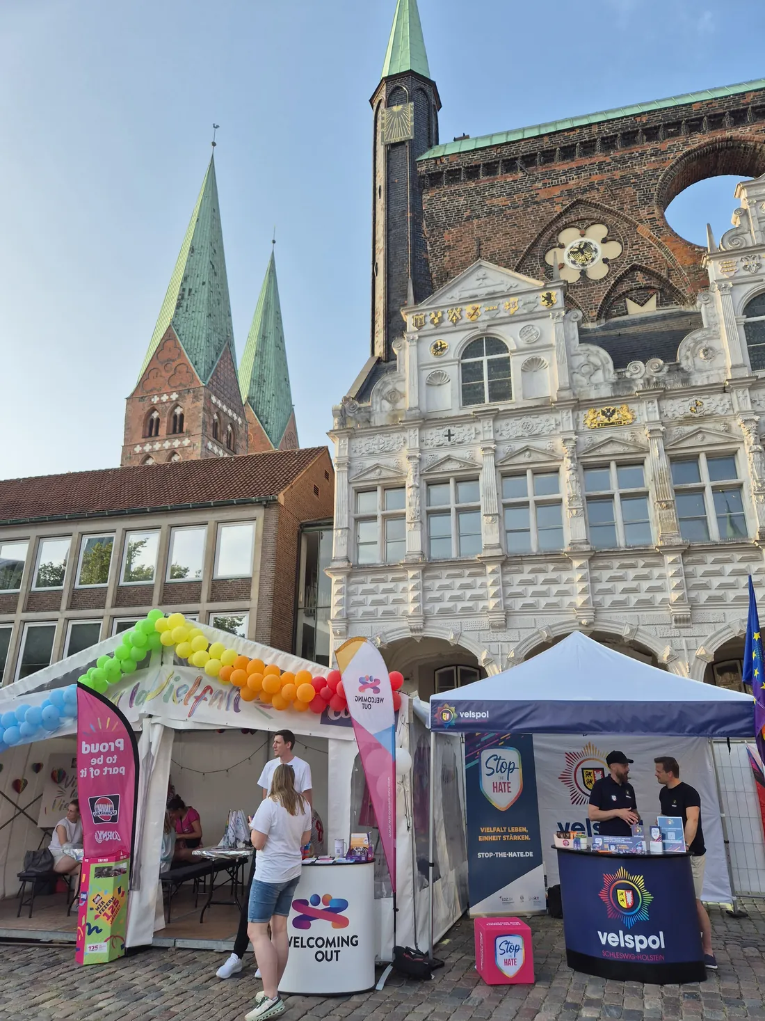 Der Marktplatz mit Pavillons von Welcoming Out und velspol vor der Renaissance-Fassade des Lübecker Rathauses und den Türmen der Marienkirche.