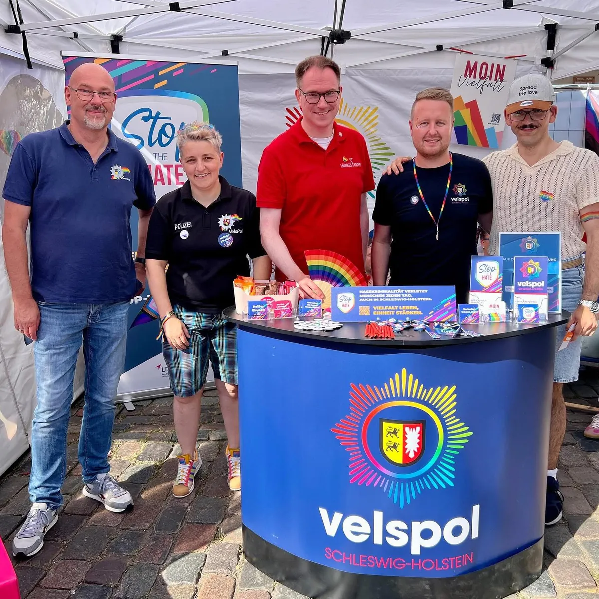 Fünf Personen hinter dem velspol-Stand, dazwischen Informationsmaterial von STOP the HATE und MOIN Vielfalt.